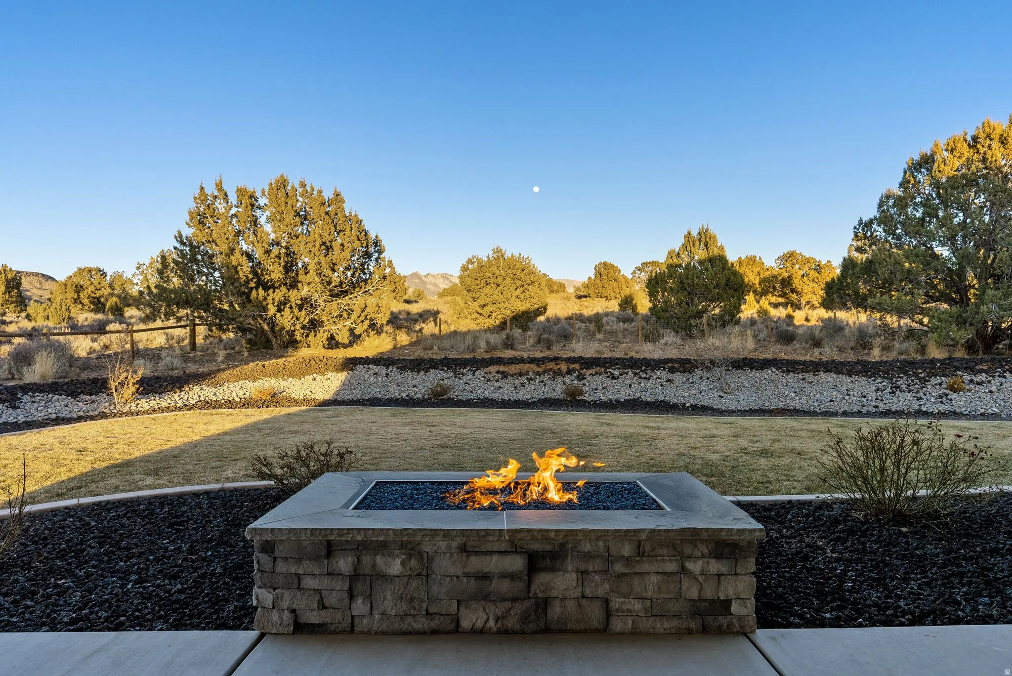 Stone-clad fire pit with a concrete cap and blue fire glass