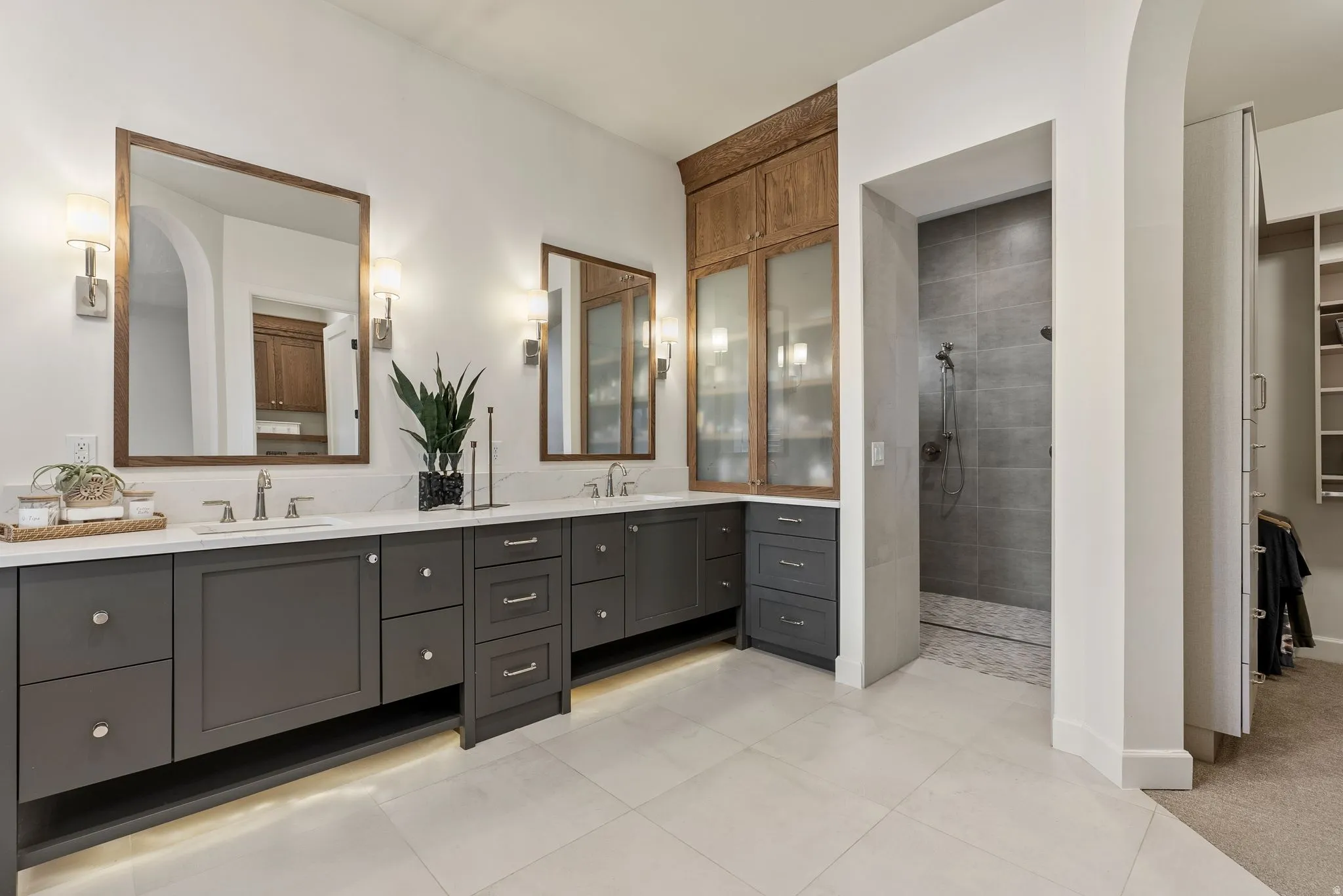 Spacious bathroom featuring dual vanities with dark cabinetry, white countertops, and undermount sinks