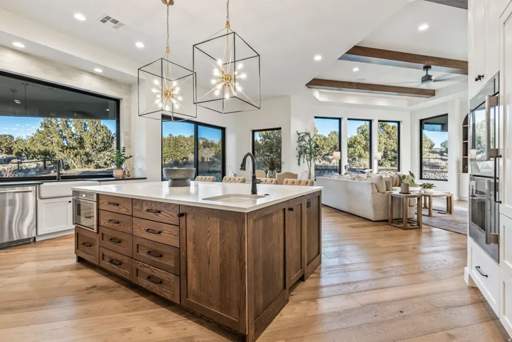 Gourmet kitchen featuring a large wood-finish island with integrated microwave, white countertops, a deep farmhouse sink, and stainless steel appliances