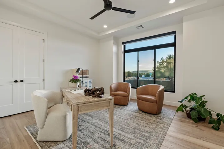 Bright interior space featuring a large window with black framing, tray ceiling, recessed lighting, and light wood-finish flooring