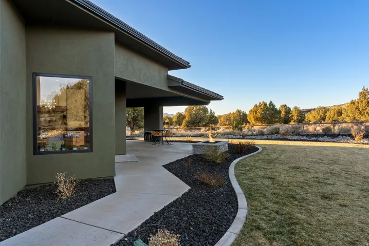 Expansive outdoor patio with a built-in fire pit, covered seating area, and a large lawn