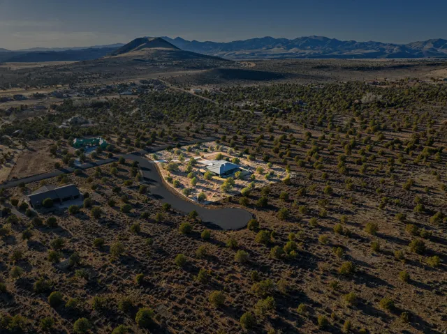 Expansive desert landscape featuring a paved residential road and distant mountain ranges