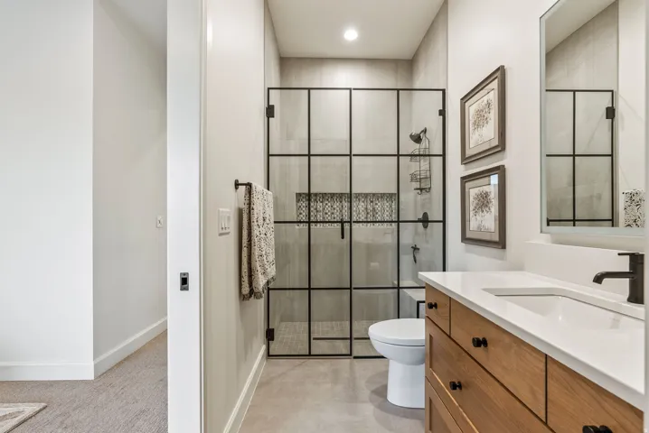 Bathroom featuring a glass-enclosed shower with black grid accents, a tiled shower niche, and a contrasting patterned accent tile