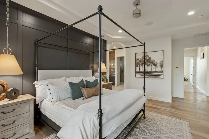 Bedroom featuring a dark paneled accent wall and light wood-finish flooring