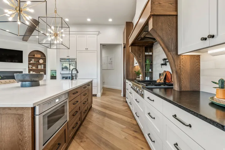 Gourmet kitchen featuring a substantial central island with integrated microwave, wood-finish flooring with a herringbone pattern, white subway tile backsplash, professional-grade range, and custom wood-finish range hood