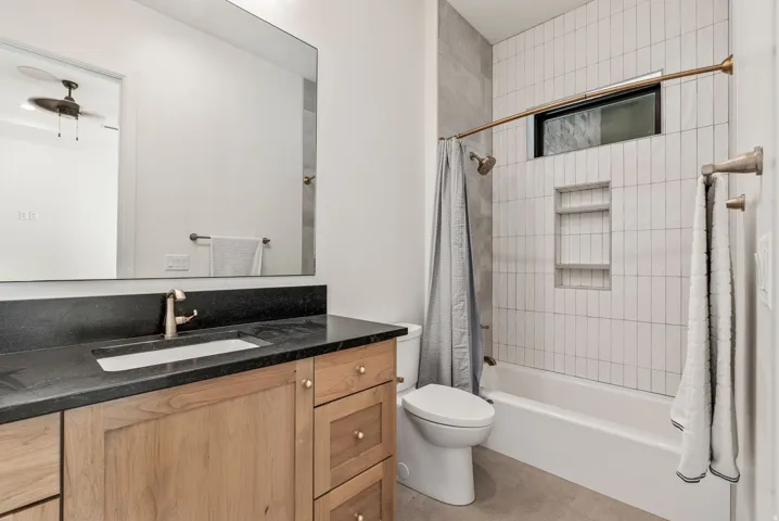 Bathroom featuring a wood-finish vanity with a built-in sink, dark countertop, and large wall-mounted mirror