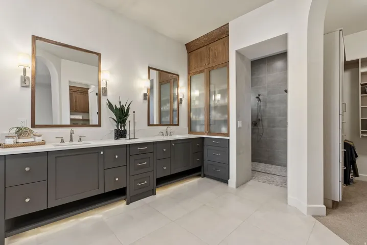 Spacious bathroom featuring dual vanities with dark cabinetry, white countertops, and undermount sinks
