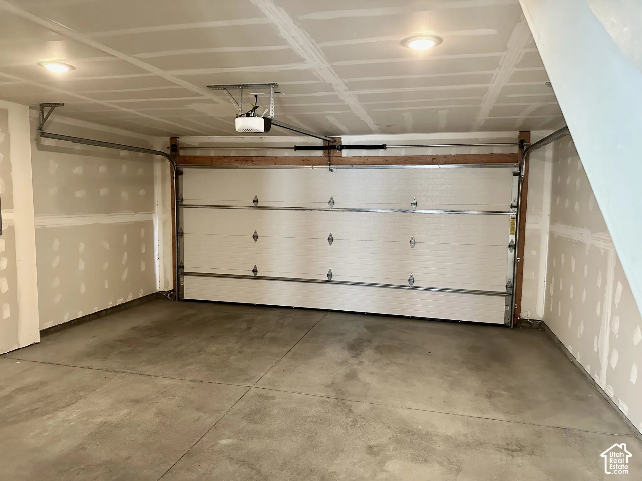 Attached garage featuring a concrete floor, automatic garage door opener, and recessed ceiling lighting