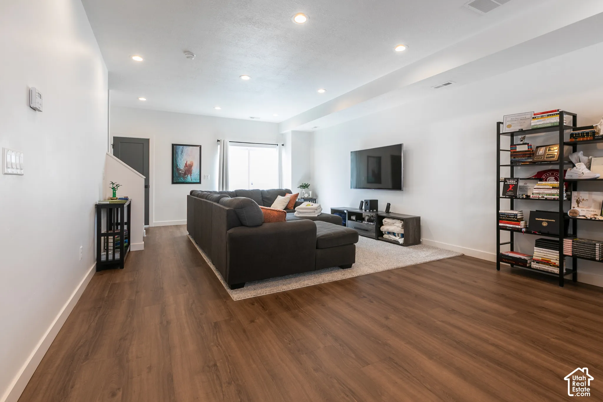 Spacious living area featuring wood-finish flooring, recessed lighting, and a large sliding glass door