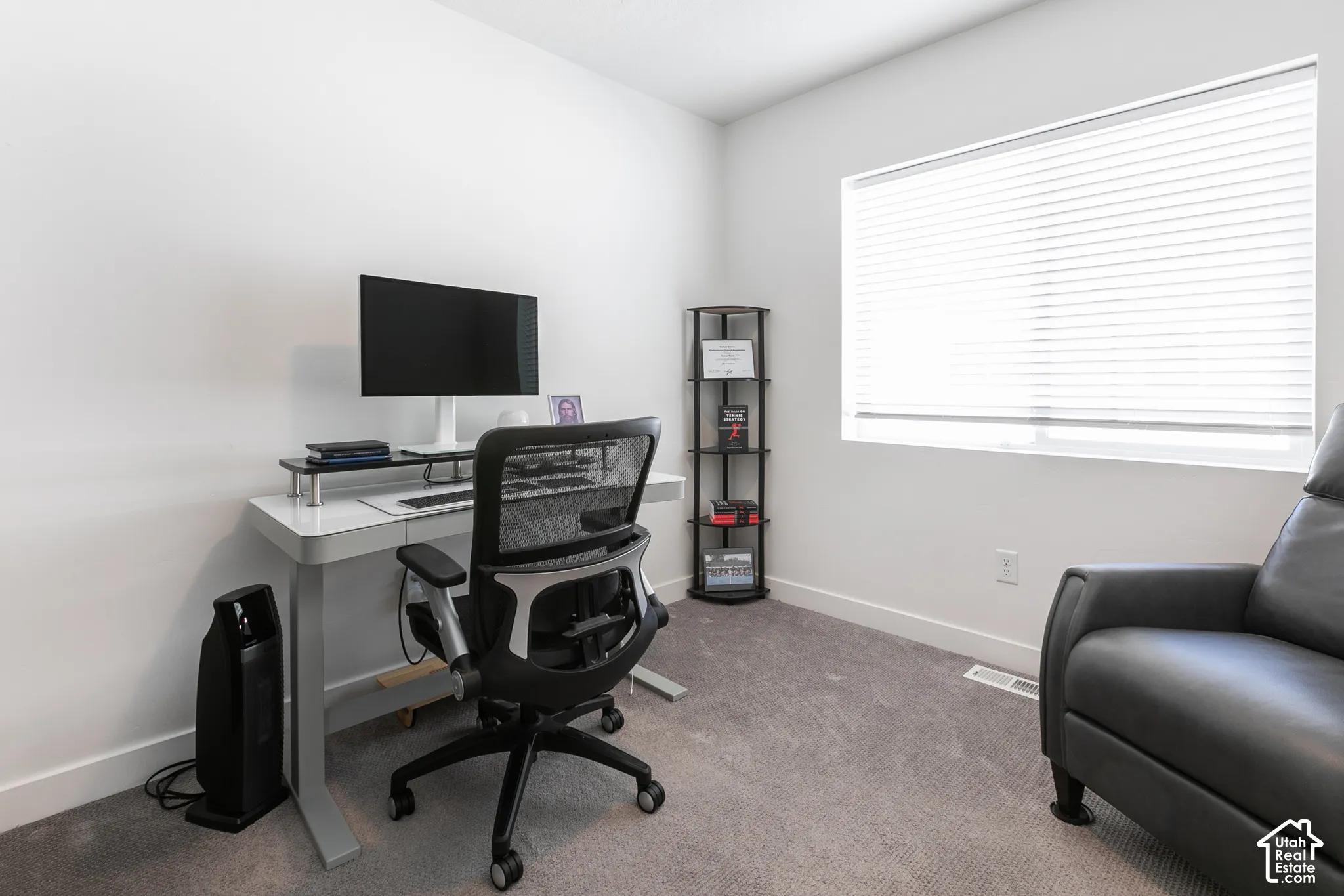 Bright room featuring a large window with horizontal blinds, neutral wall paint, and gray carpet flooring