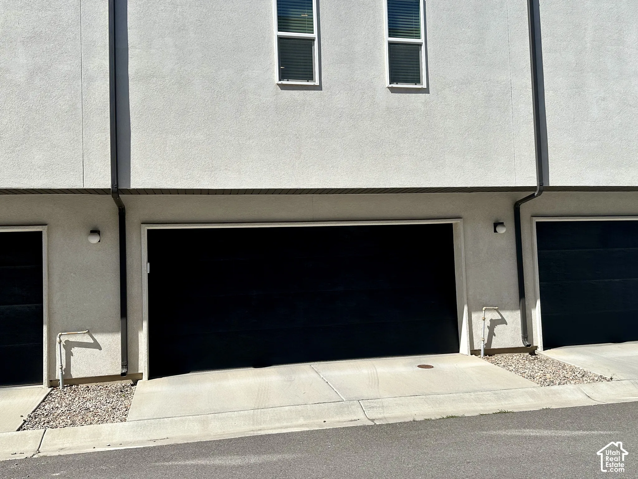 Stucco exterior with multiple garage bays, concrete driveways, and gravel landscaping accents