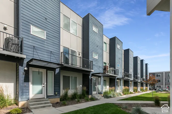 Contemporary multi-level exterior featuring horizontal lap siding, panel facade, metal-frame upper-level balconies, and glass-accented entry doors with cantilevered awnings