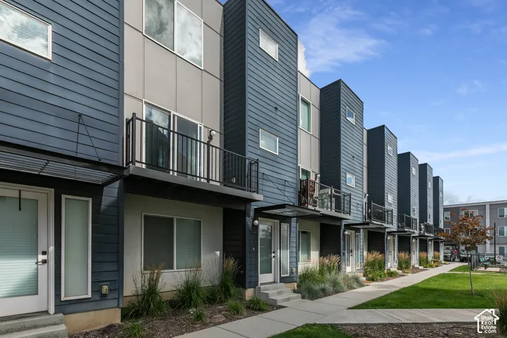Modern exterior featuring horizontal lap siding, metal paneling, integrated balconies with metal railings, and concrete walkways