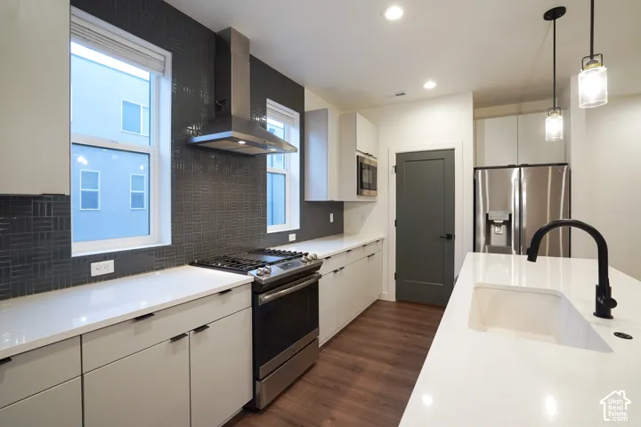 Kitchen featuring flat-panel cabinetry, quartz countertops, dark geometric tile backsplash, stainless steel appliances, and wood-finish flooring