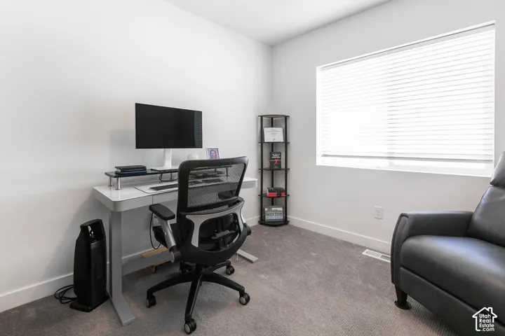 Bright room featuring a large window with horizontal blinds, neutral wall paint, and gray carpet flooring