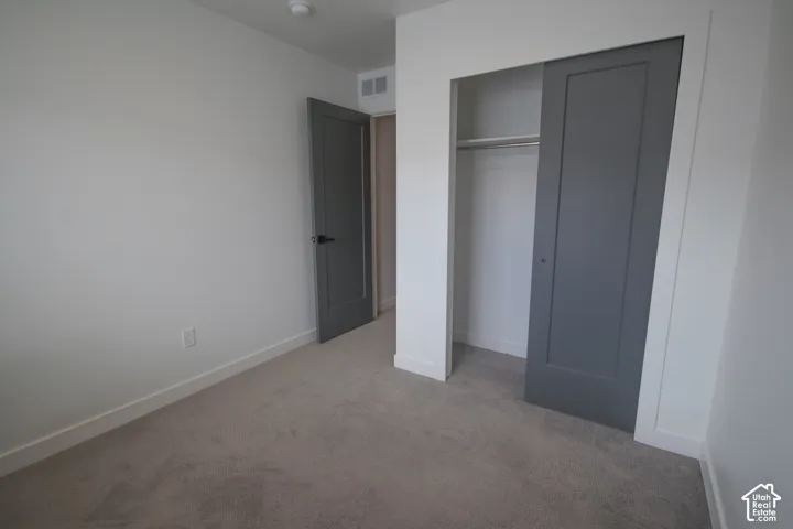 Room featuring neutral carpeting, a sliding door closet with a built-in rod, and gray shaker-style doors with matte black hardware