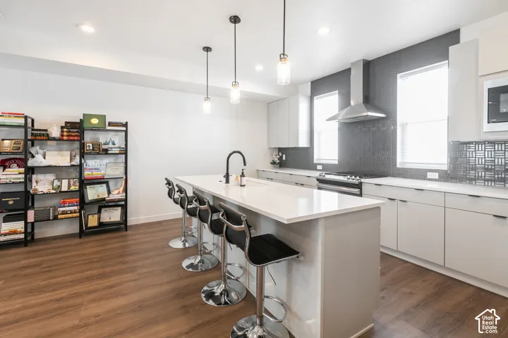 Modern kitchen featuring a large island with white countertop, sleek light cabinetry, and stainless steel appliances