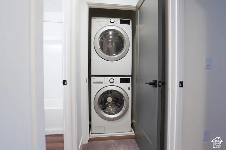 Laundry closet featuring stacked high-efficiency appliances, solid-core painted interior door, and matte black hardware