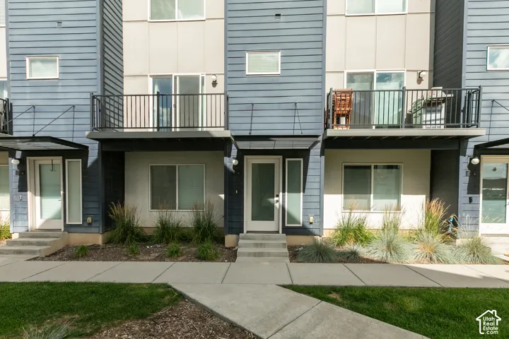 Contemporary multi-level exterior featuring horizontal lap siding, panel facade elements, private metal-railed balconies, and ground-level concrete entryways