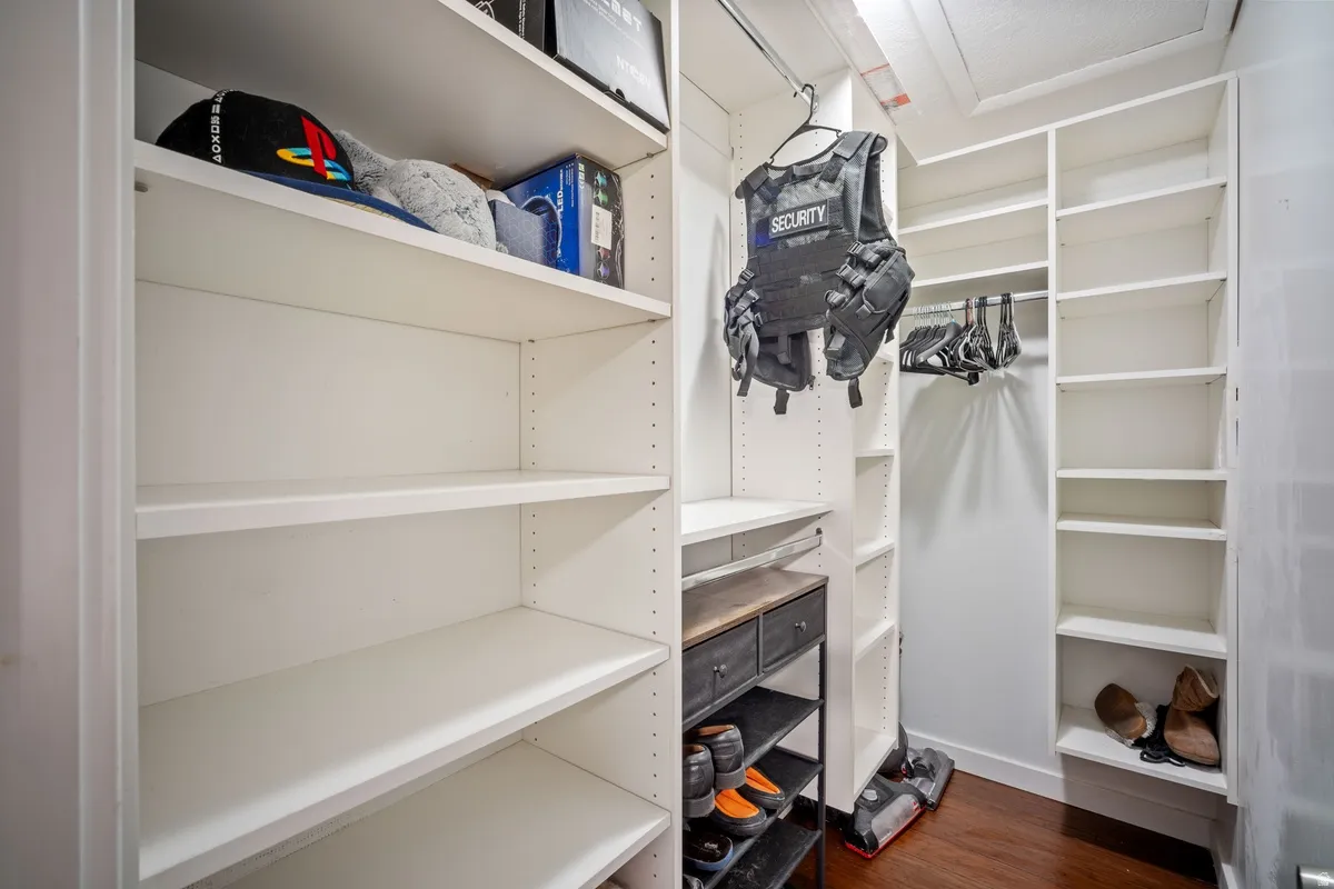 Custom closet system featuring white shelving, multiple hanging rods, and a dark wood-finish shoe rack with integrated drawers