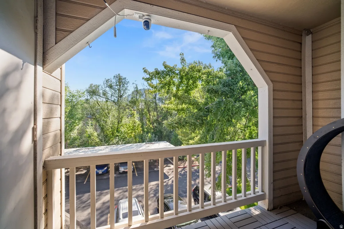 Private balcony with slatted wood flooring, white wooden railing, and a vaulted ceiling feature