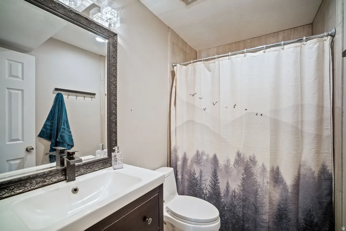 Bathroom featuring a dark wood-finish vanity with an integrated sink, an ornate framed mirror, a modern faucet, and a contemporary light fixture