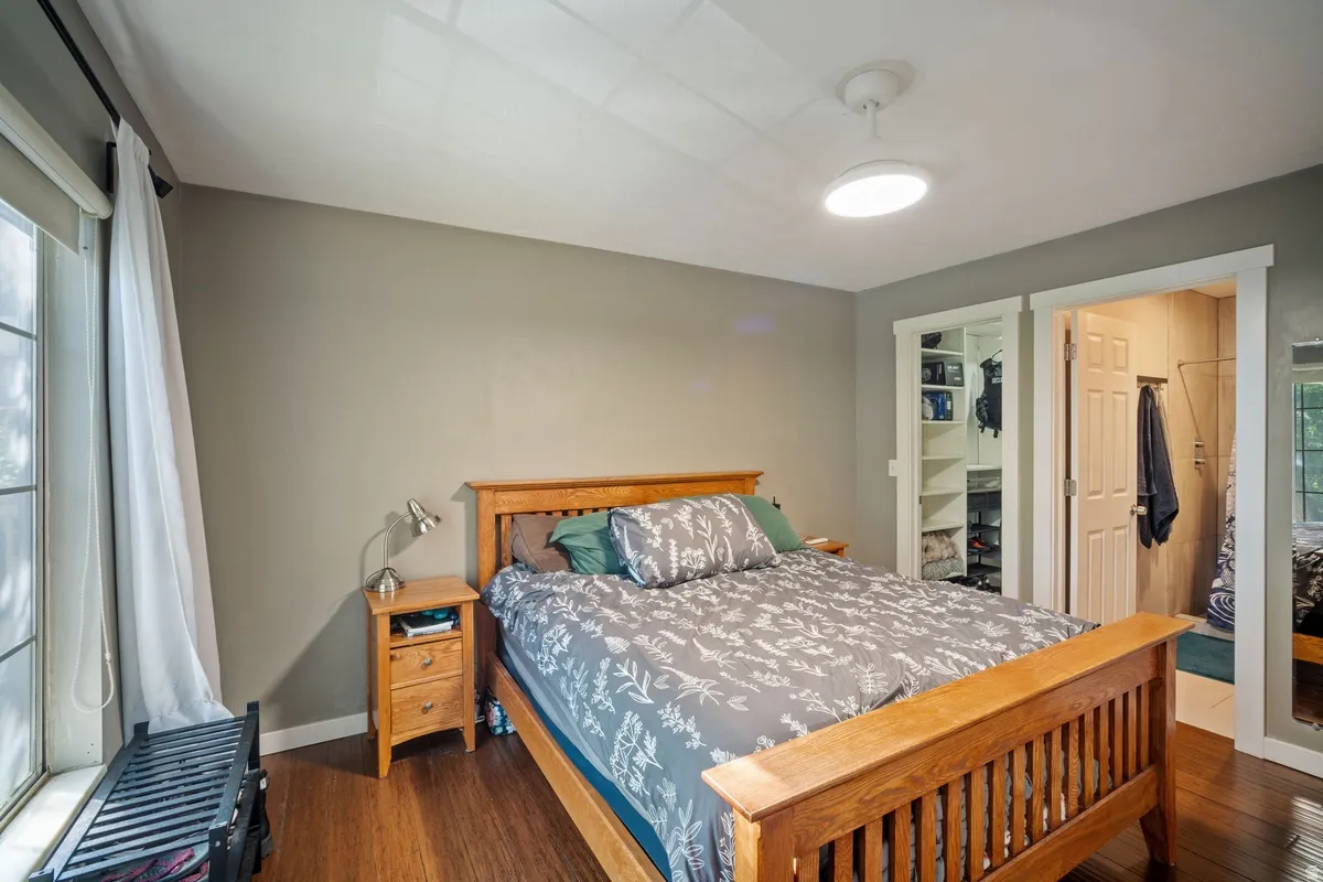 Bedroom featuring wood-finish flooring, a ceiling-mounted light fixture, and a window with white trim
