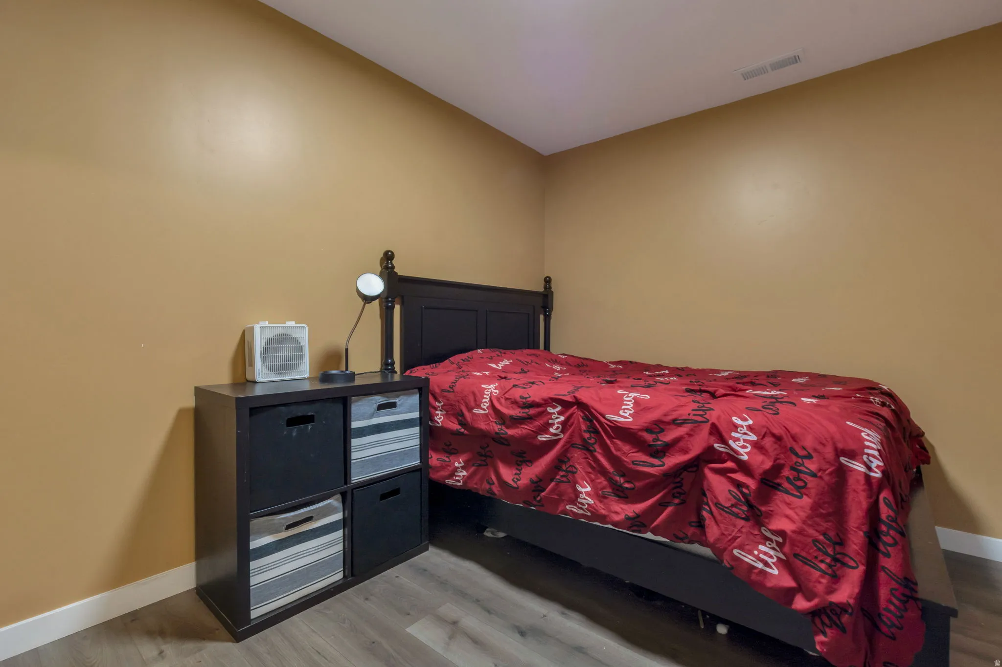 Bedroom featuring neutral-toned walls, wood-finish flooring, white baseboards, and a ceiling vent