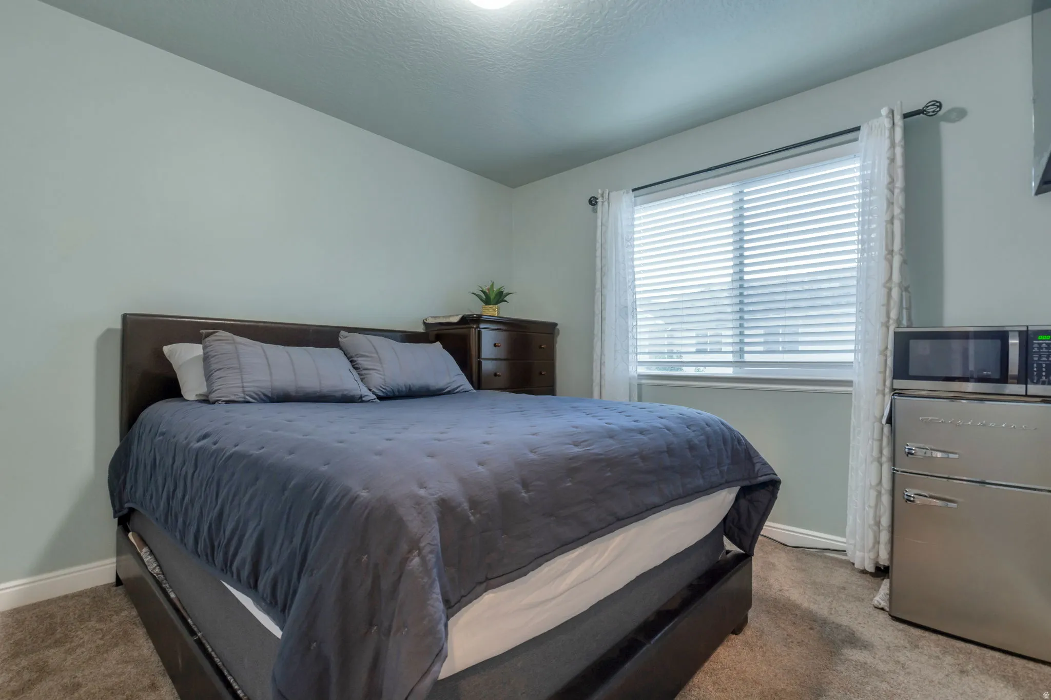 Neutral-toned walls complement the window with horizontal blinds and drapes