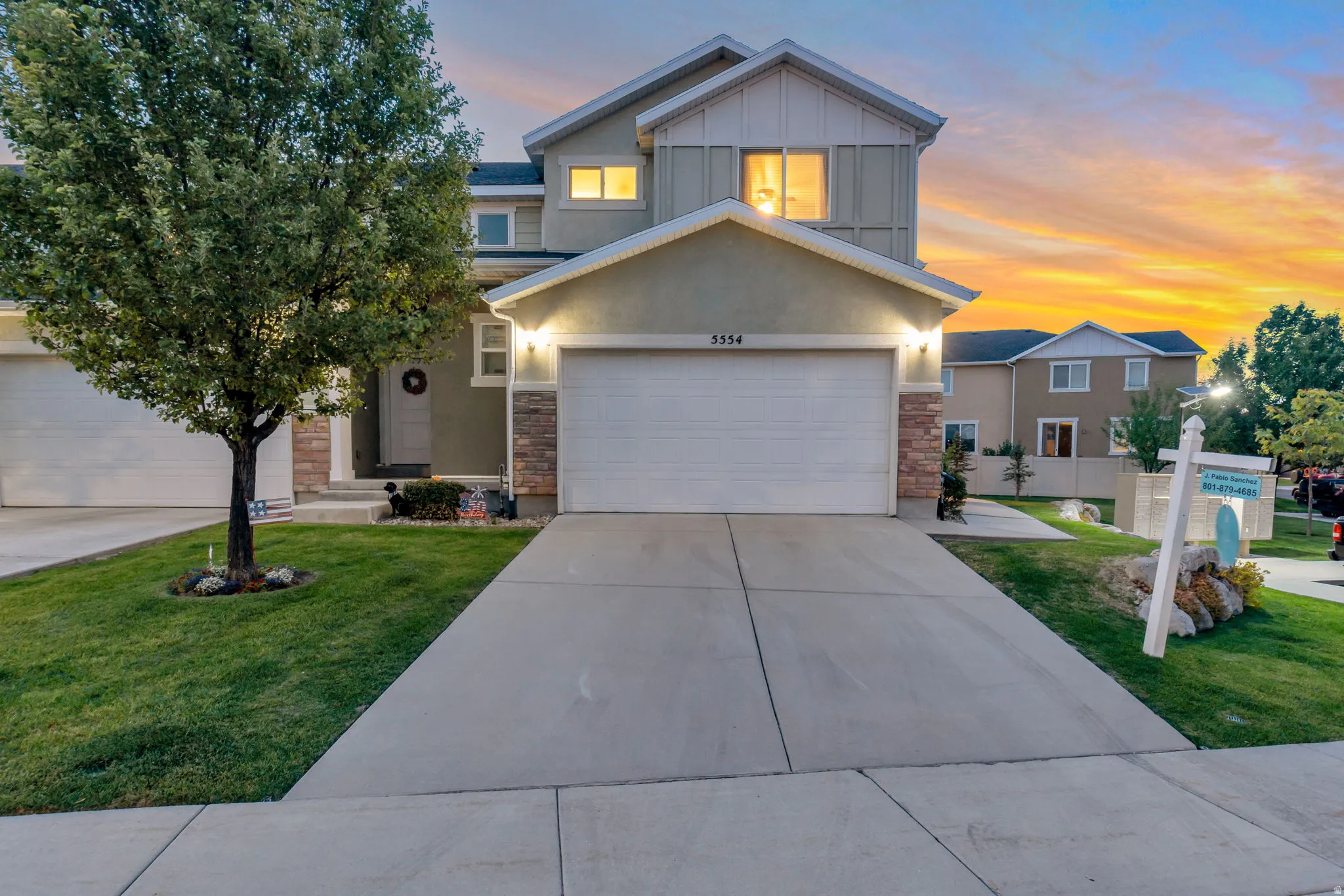 Two-story residence featuring a two-car garage, concrete driveway, and stone accents