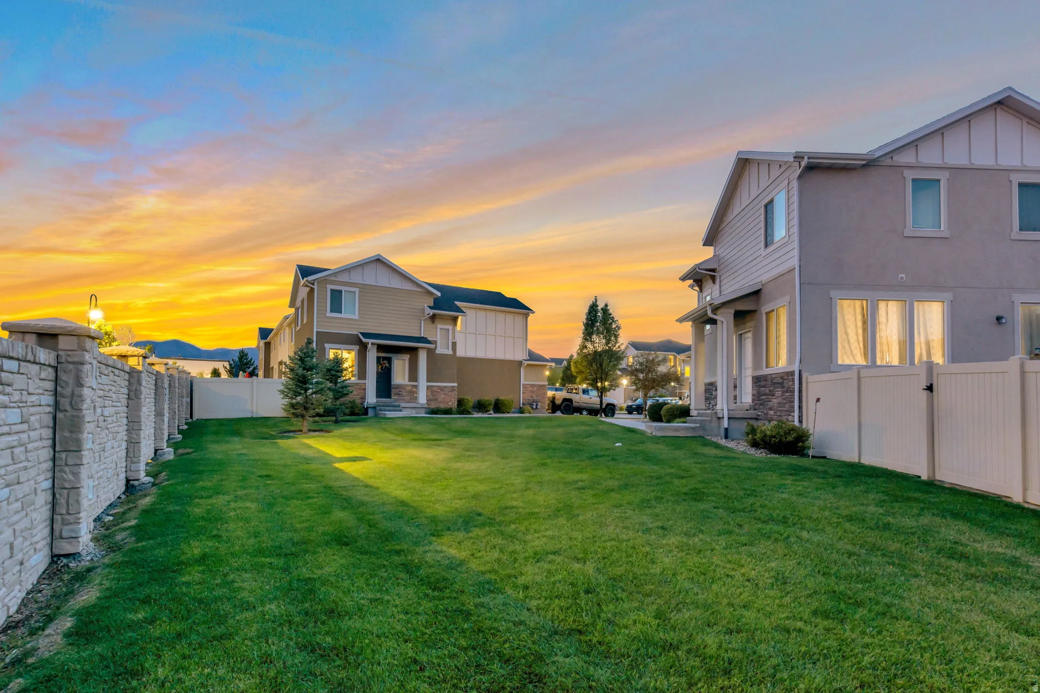 Expansive grassy yard area with a stone-finish perimeter wall and white privacy fencing