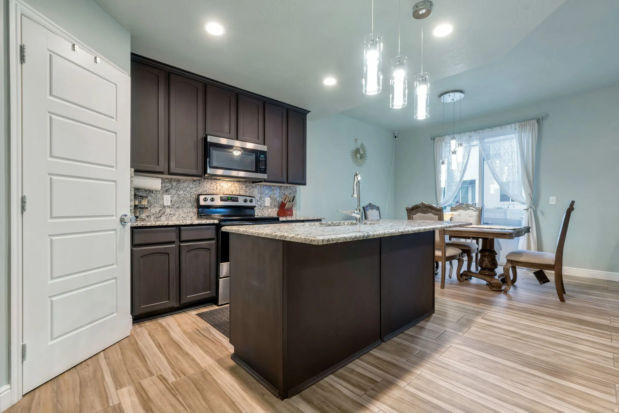 Kitchen featuring wood-finish flooring, dark cabinetry, and light-toned countertops