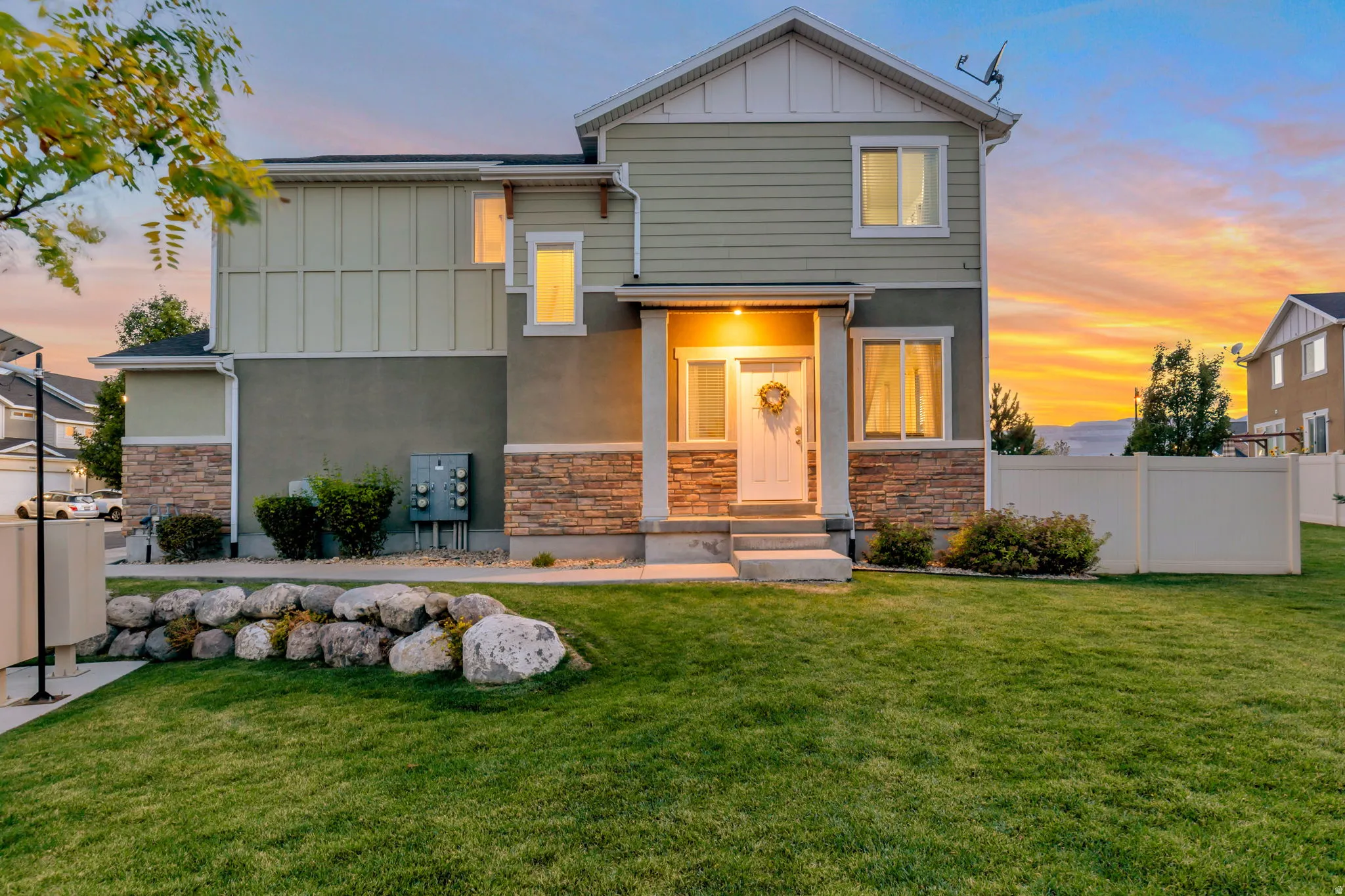 Two-story residence featuring light green siding and stone veneer accents