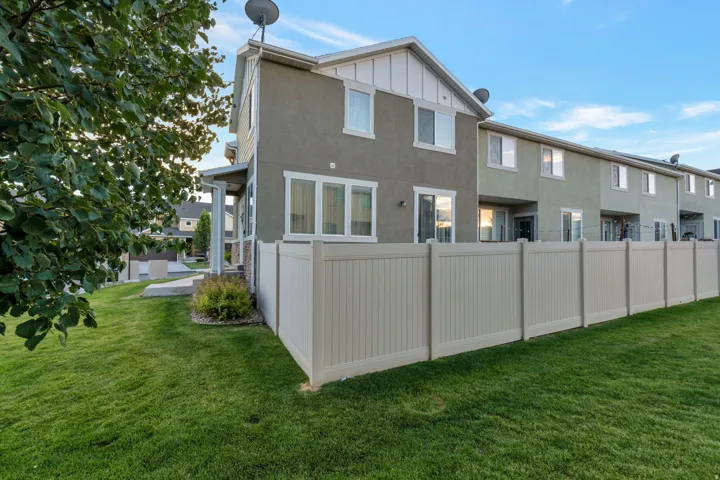Fenced backyard featuring a manicured lawn, an extended patio, and stucco exterior