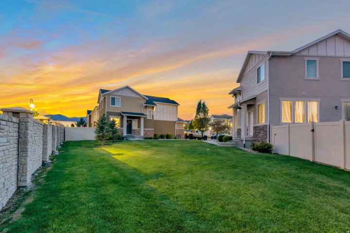 Expansive grassy yard area with a stone-finish perimeter wall and white privacy fencing