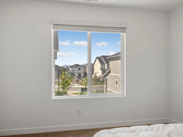 Double-pane window featuring white trim and horizontal blinds, set within a white wall with carpeted flooring