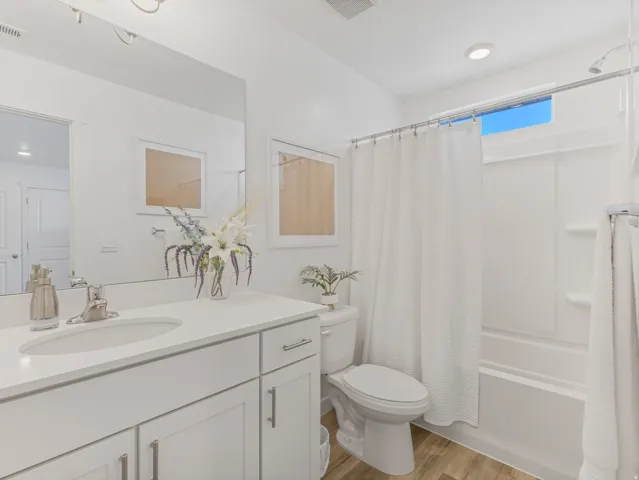 Bright bathroom featuring a single vanity with an integrated sink, white cabinetry, and brushed nickel hardware