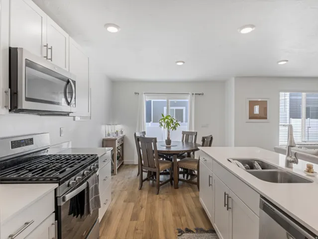 Modern kitchen featuring white cabinetry, stainless steel appliances, wood-finish flooring, recessed lighting, and a kitchen island with an undermount sink