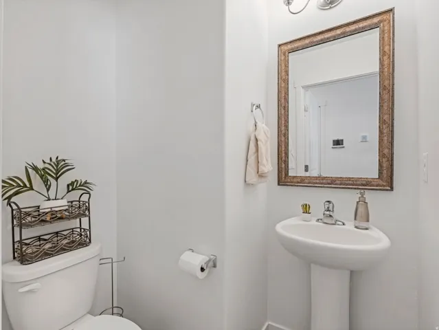 Pedestal sink with chrome faucet, complemented by an ornate framed mirror and a two-light vanity fixture