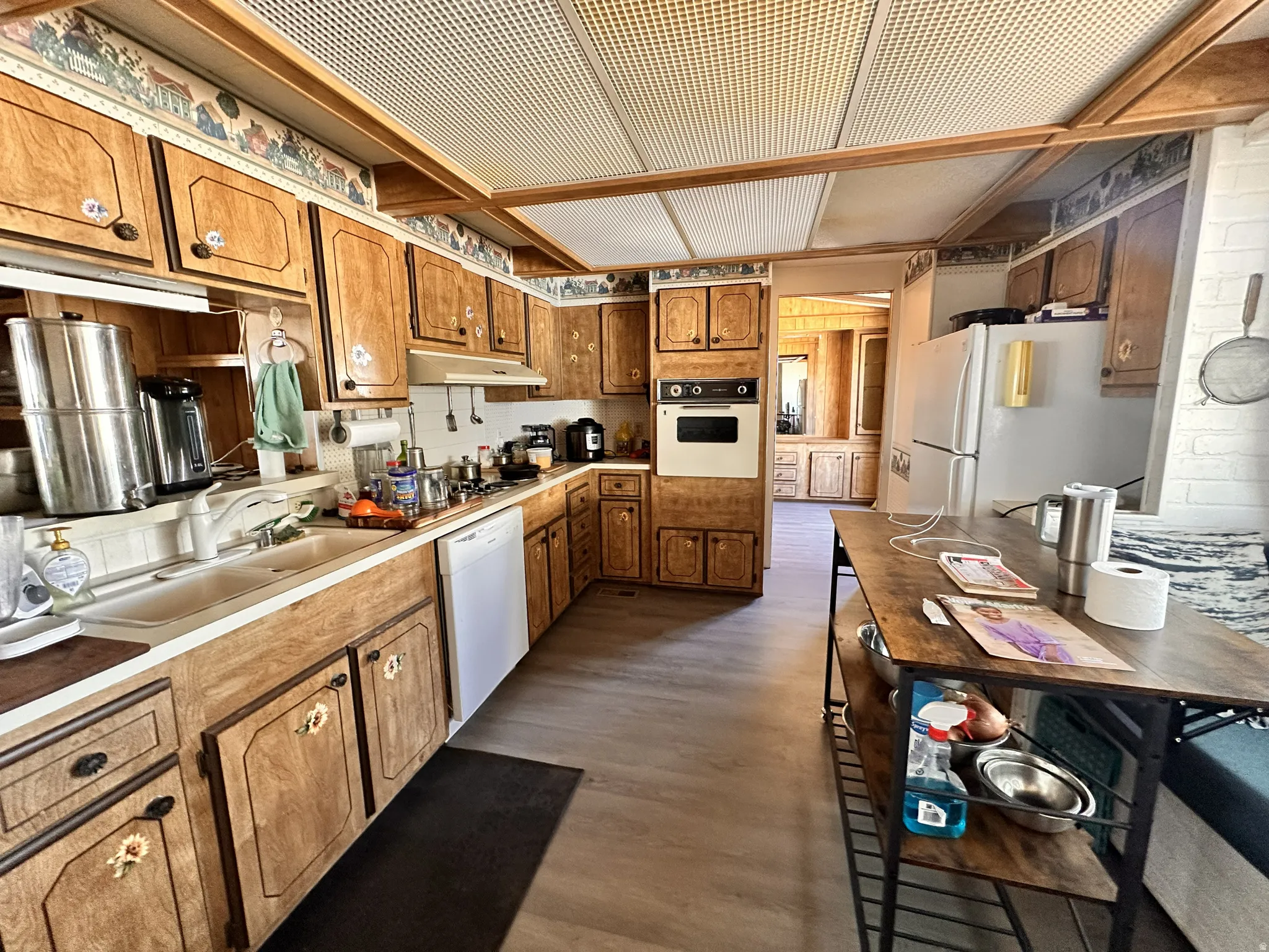 Kitchen featuring wood-finish cabinetry, built-in wall oven, and white appliances