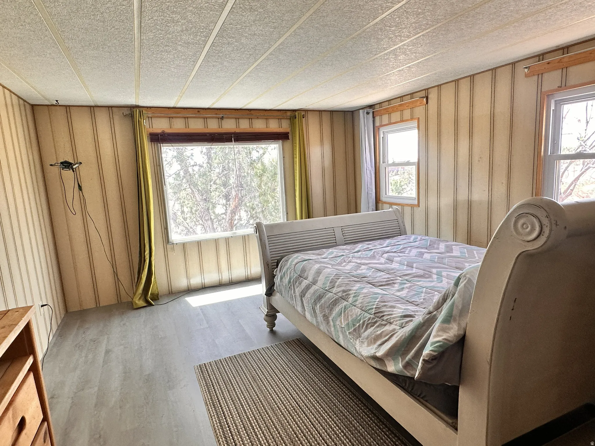 Room featuring wood-finish flooring, vertical paneling, and multiple windows
