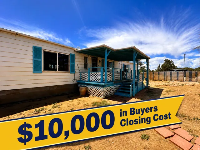 White siding exterior with a covered porch featuring blue trim and white lattice detailing, blue window shutters, and a simple front entrance