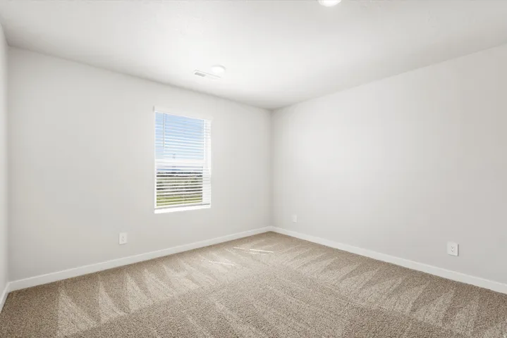Bright interior room featuring neutral-toned walls, recessed lighting, and patterned carpet flooring