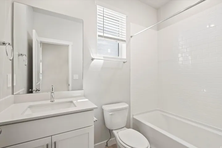 Bathroom featuring a white vanity with an integrated sink, polished chrome faucet, and a large frameless mirror