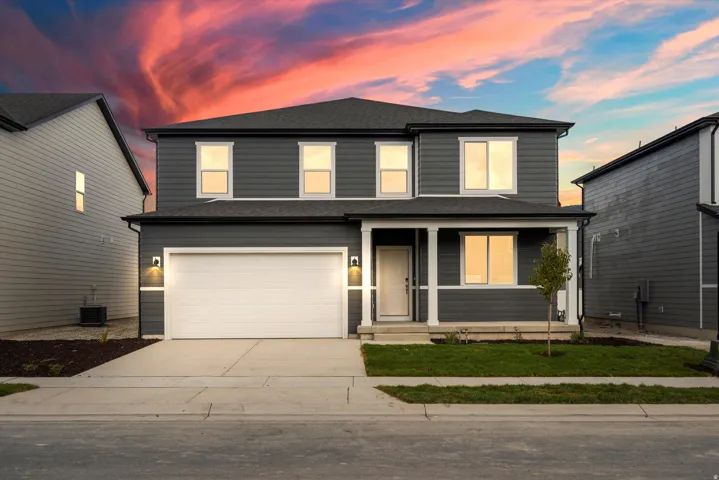 Two-story residence featuring dark siding, white trim accents, and a covered front porch with white columns