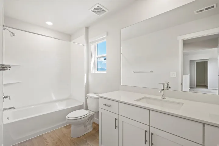 Modern bathroom featuring a single vanity with a white countertop and undermount sink, chrome faucet, and a large wall-mounted mirror