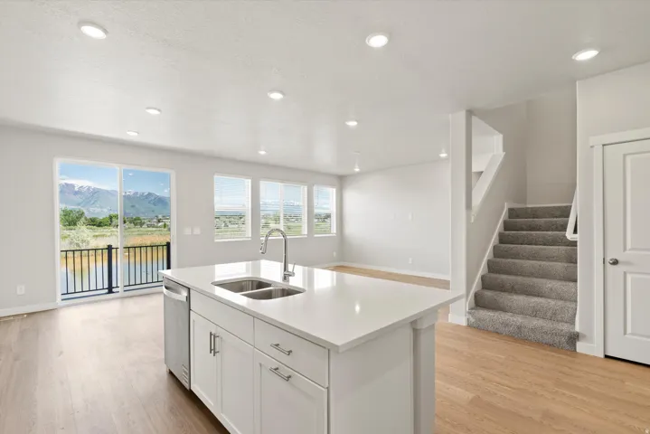 Kitchen island with an undermount dual-basin stainless steel sink, a stainless steel dishwasher, and white cabinetry