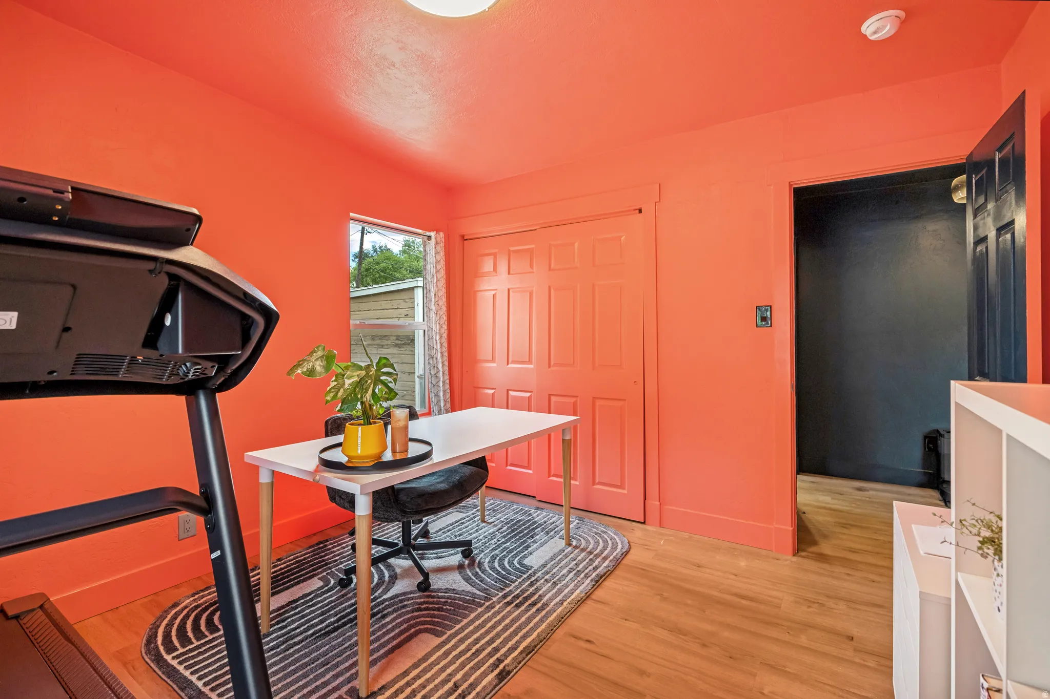 Room featuring vibrant coral walls, wood-finish flooring, and a window with natural light