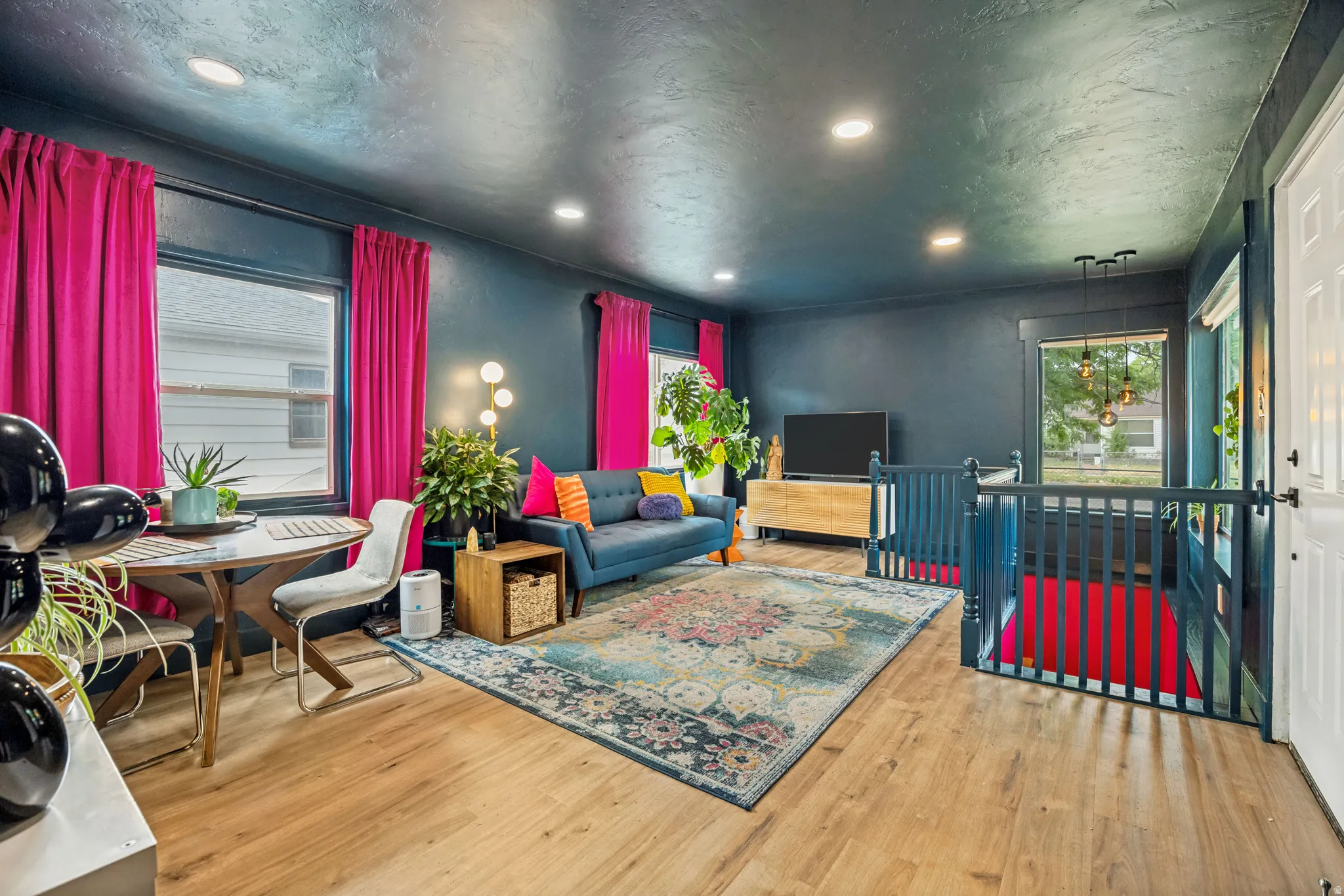 Bright living area featuring wood-finish flooring, recessed lighting, and a built-in staircase with railings