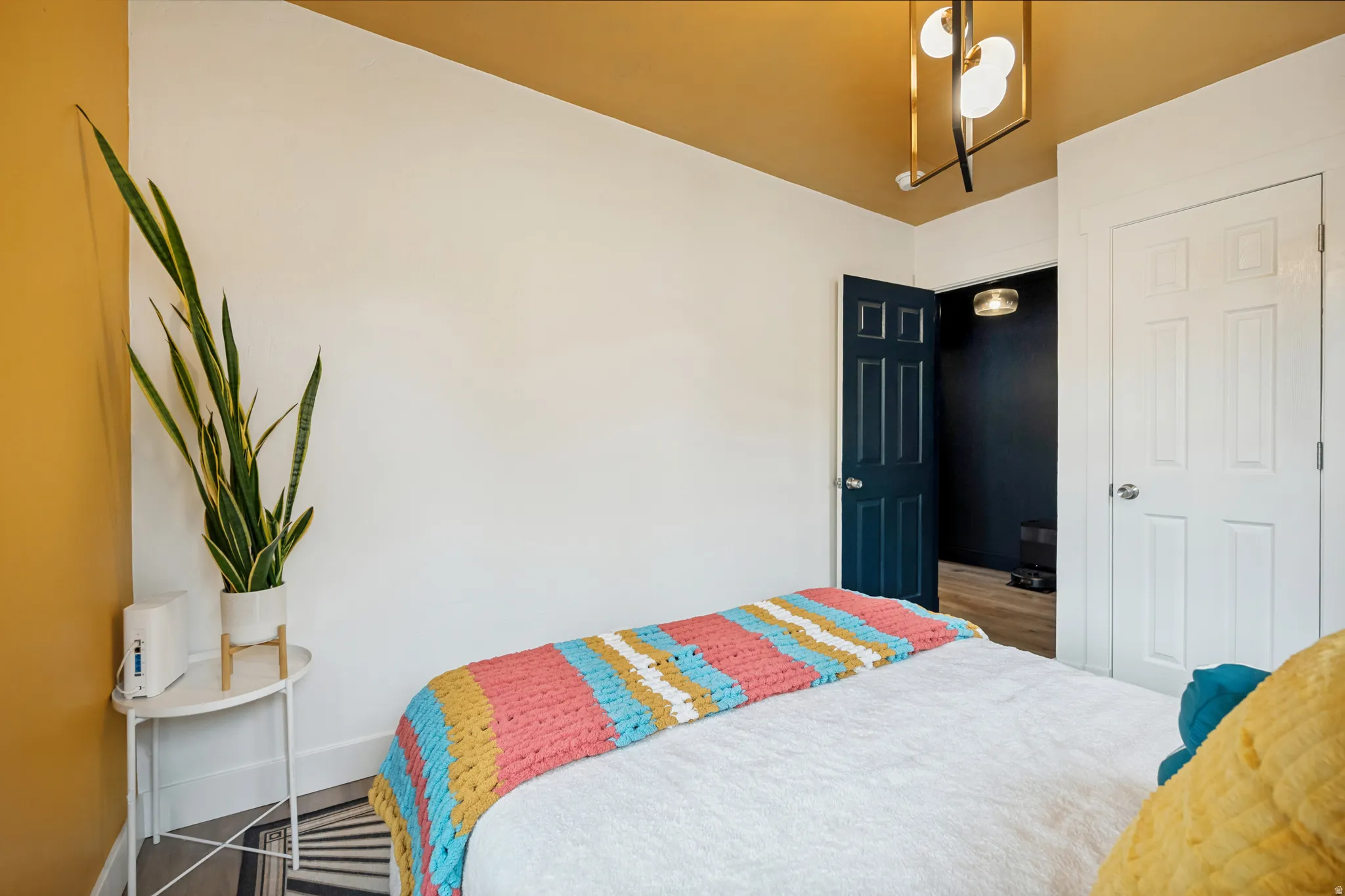 Bedroom featuring white walls and a contrasting accent wall, a modern ceiling light fixture, and a paneled door